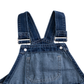 Close-up of the back of dark blue denim overall with adjustable shoulder straps, metal buckles, and a back pocket on a white background.